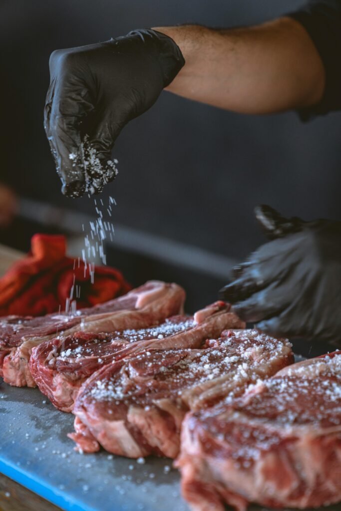 pexels photo 8477228 8477228 A chef seasons raw steaks with sea salt, perfecting the preparation process.